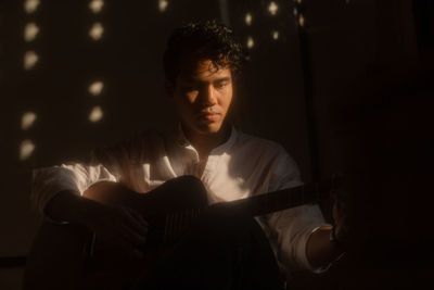 Young man sitting in the dark