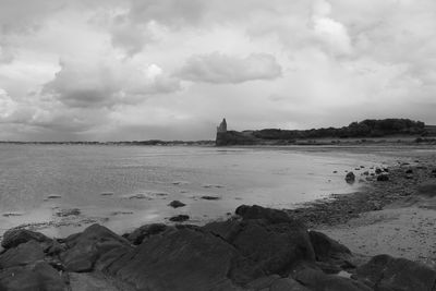 View of statue on beach against cloudy sky