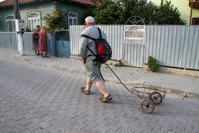 Full length rear view of man walking on footpath