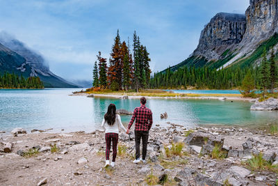 Rear view of people on lake against mountain range