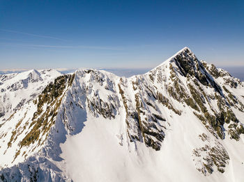 Scenic view of snow covered mountains against blue sky