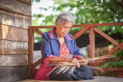Woman weaving wicker in hut