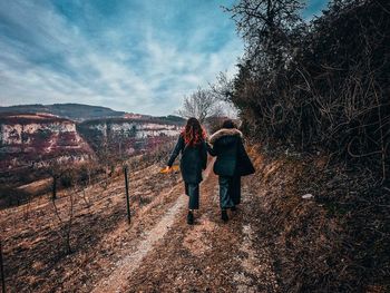 Rear view of woman walking on road against sky