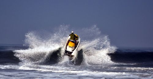Rear view of man riding jet boat on sea against sky