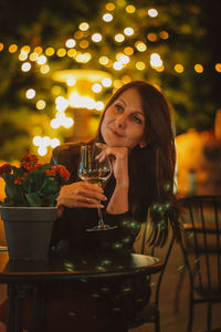 Portrait of young woman drinking glass on table