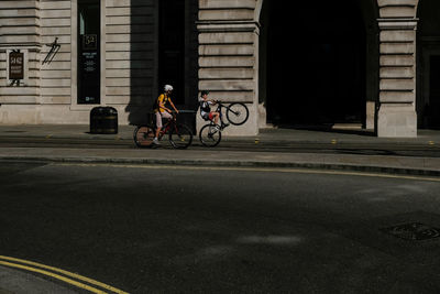 Man riding motor scooter on street against building