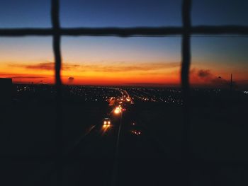 Silhouette of cars moving on road at sunset