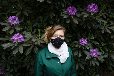 Portrait of beautiful young woman standing by flowering plants