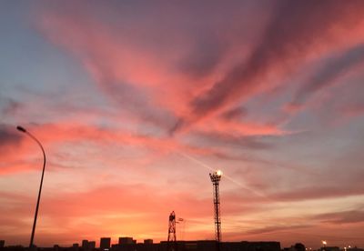 Silhouette of street lights against dramatic sky during sunset