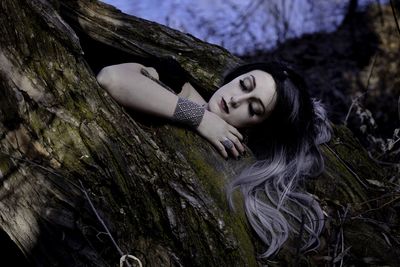 Low angle view of young woman embracing on tree
