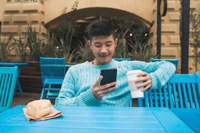 Young man using mobile phone while sitting on table