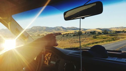 Cropped hand pointing while driving car by landscape