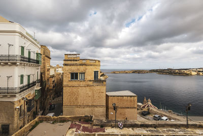 Buildings by river against sky