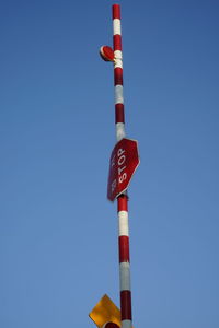 Low angle view of road sign against clear blue sky