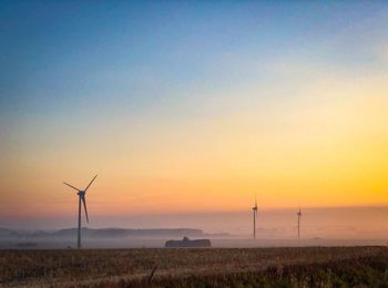 Windmill on field against sky during sunset