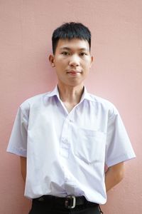 Portrait of young man standing against wall