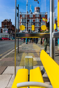 Yellow empty bench at bus stop in city