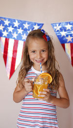 Portrait of young woman holding glass of refreshing beverage with orange 