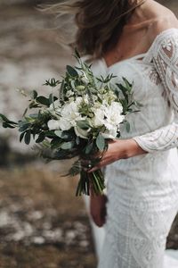 Midsection of bride holding bouquet