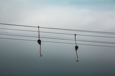 Low angle view of silhouette cable car against sky