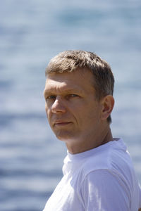 Portrait of mature man against sea on sunny day