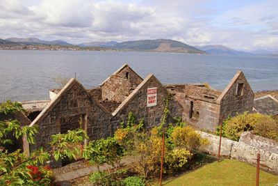 Houses by lake and buildings against sky