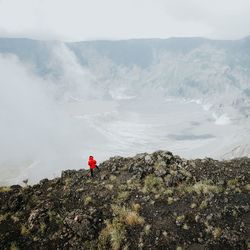 Man standing on rock against volcanic landscape