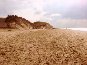 Scenic view of beach against cloudy sky at sunset