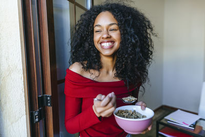 Portrait of laughing young woman eating cereals