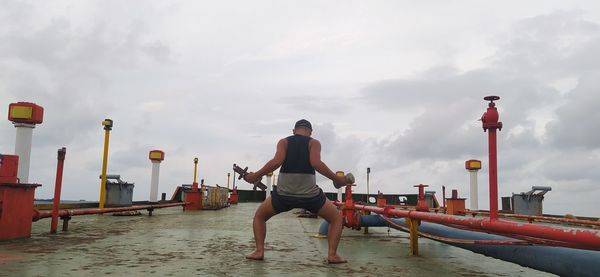 Rear view of man standing by sea against sky