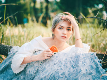 Portrait of beautiful young woman lying on land