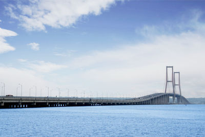 Bridge over sea against cloudy sky