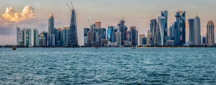 Doha skyline daylight view with arabic gulf in foreground and clouds in the sky in background 