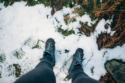 Low section of person standing on snow covered landscape