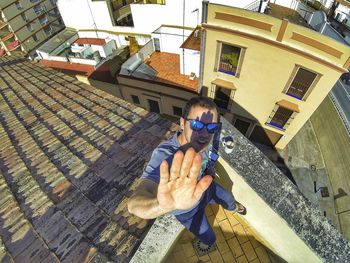 Portrait of man gesturing stop sign while standing against buildings