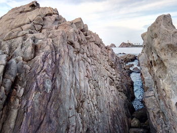 Rock formations on shore against sky