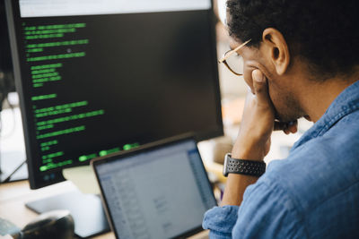 Focused male it professional using laptop while sitting in creative workplace