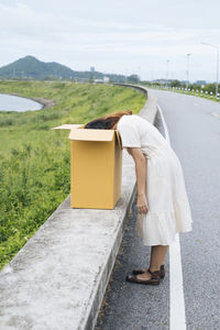 Side view of woman peeking on box on road