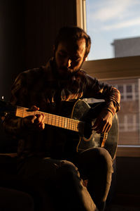 Man playing guitar at home