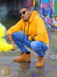 Young man looking away while sitting on water