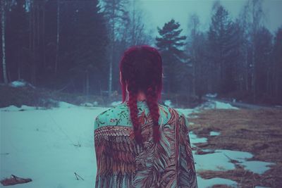 Rear view of woman standing on field during winter