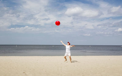 Full length of woman standing on beach against sky