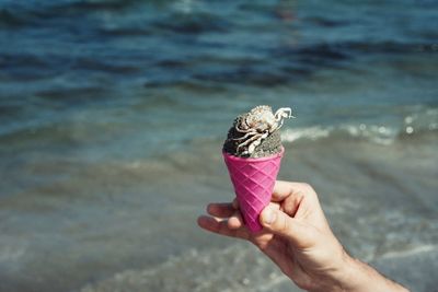 Person holding ice cream cone at beach