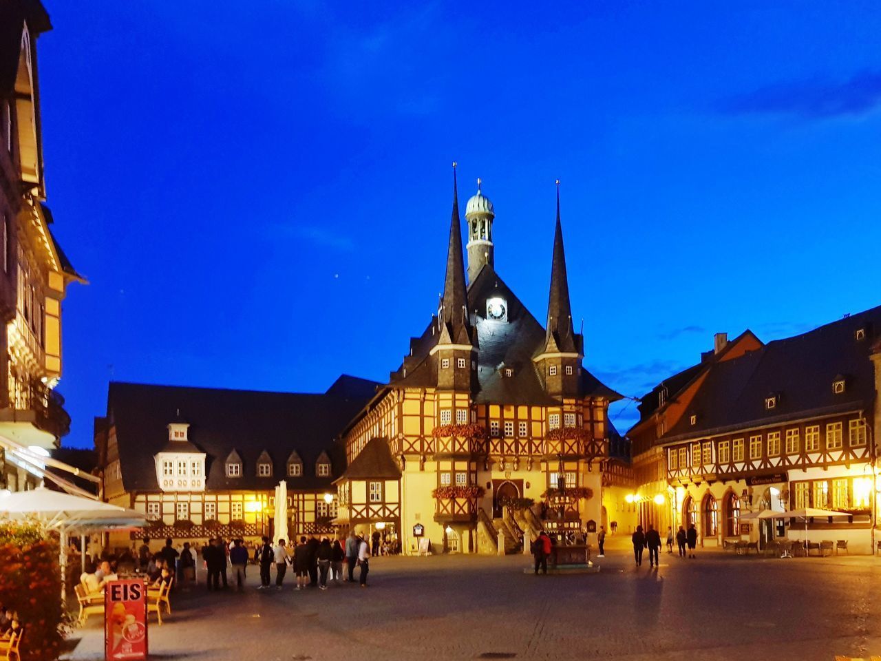 GROUP OF PEOPLE IN FRONT OF BUILDINGS AT NIGHT