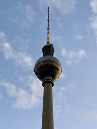 Low angle view of communications tower and building against sky