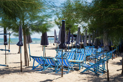 Empty chairs on sand at beach