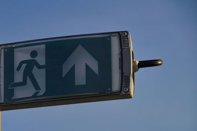 Low angle view of road sign against clear blue sky