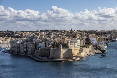 Aerial view of townscape by sea against sky