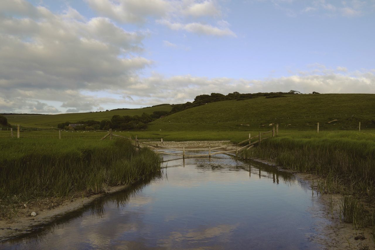 tranquil scene, sky, tranquility, water, grass, scenics, landscape, field, cloud - sky, beauty in nature, nature, reflection, cloud, rural scene, lake, cloudy, non-urban scene, river, stream, idyllic