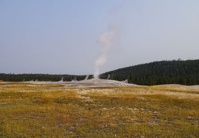 Steam emitting from volcanic landscape against clear sky